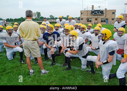 High School Football-Trainer geben aufmunternde Worte für die Spieler vor dem Training Stockfoto