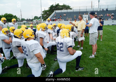 High School Football-Trainer geben aufmunternde Worte für die Spieler vor dem Training Stockfoto