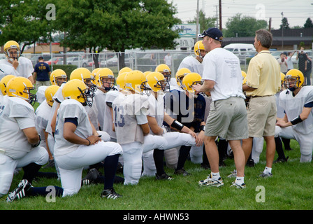 High School Football-Trainer geben aufmunternde Worte für die Spieler vor dem Training Stockfoto