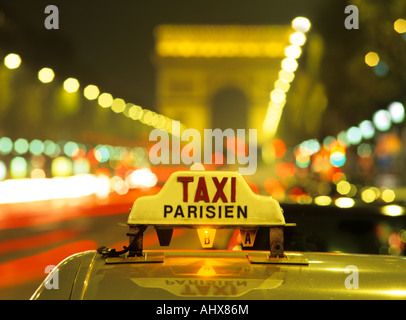 Parisien Taxi auf Champs-Élysées in der Nacht mit Arc de Triomphe im Hintergrund Stockfoto