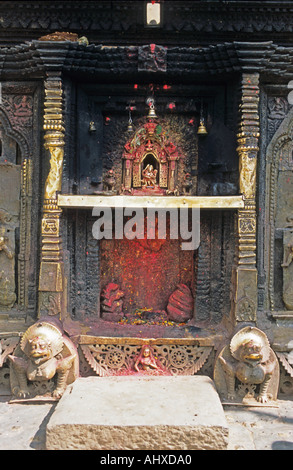 Reich verzierter Hindusteinschrein mit Goldakzenten, rotem Sindopulver und Löwenstatuen an der Basis in Kathmandu, Nepal. Stockfoto