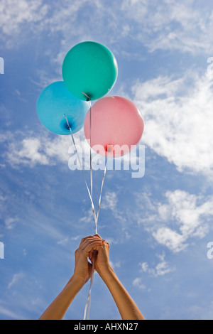 Hände halten Ballons in Richtung Himmel Stockfoto