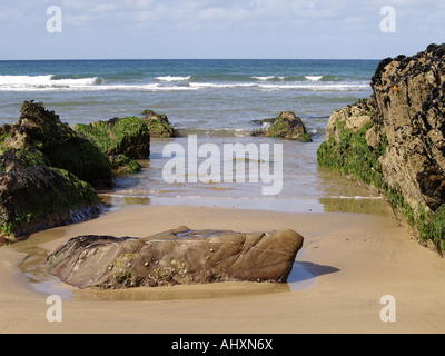 kleiner Sandstrand mit großen Felsen in der Mitte, und ein ruhiges Meer Stockfoto