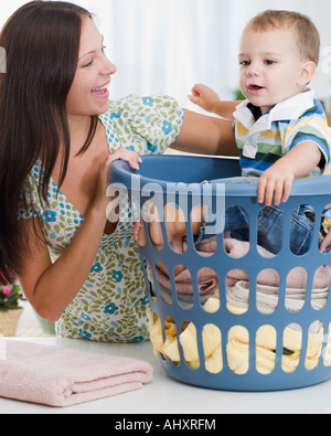 Mutter lächelte Baby im Wäschekorb Stockfoto