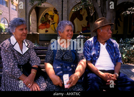 3 Drei Mexikaner, mexikanische Frauen und Männer Freunde sitzen auf einer Parkbank in Plaza Tapatia in Guadalajara in Jalisco in Mexiko Stockfoto