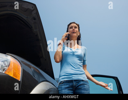 Frau am Handy als nächstes, Auto kaputt Stockfoto