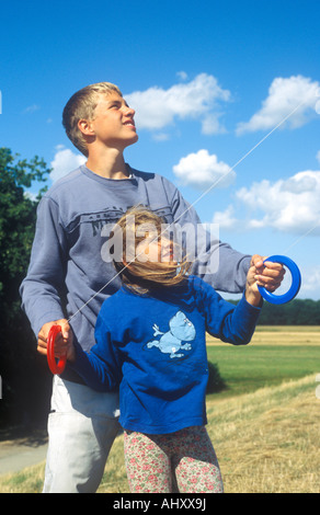 ein älterer Bruder hilft seine jüngere Schwester, einen Drachen zu fliegen Stockfoto