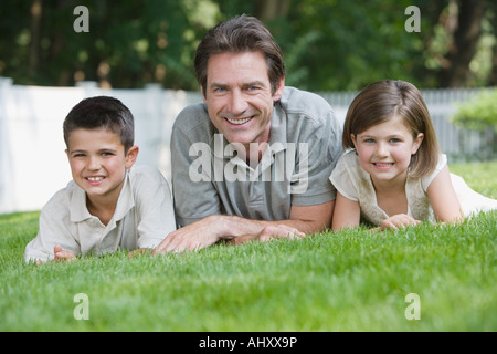 Vater und Kinder Verlegung in Rasen Stockfoto