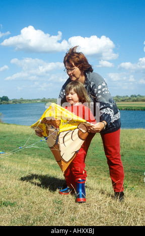 eine Mutter und ihre kleine Tochter fliegen einen Drachen zusammen Stockfoto