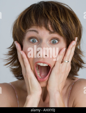 Frau, die mit den Händen auf Wangen überrascht Stockfoto