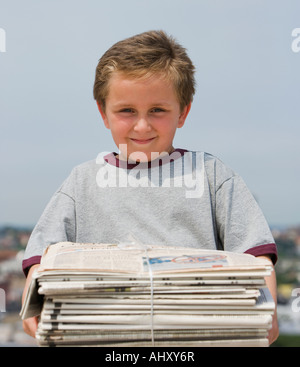 Junge hält Stapel gebündelten Zeitungen Stockfoto
