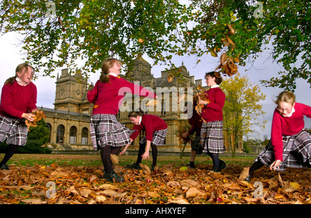 MÄDCHEN AUS WESTONBIRT SCHULE IN DER NÄHE VON TETBURY GLOUCESTERSHIRE UK SPIELEN MIT DEM HERBSTLAUB Stockfoto