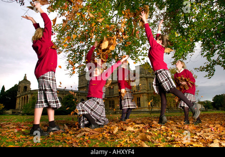 MÄDCHEN AUS WESTONBIRT SCHULE IN DER NÄHE VON TETBURY GLOUCESTERSHIRE UK SPIELEN MIT DEM HERBSTLAUB Stockfoto