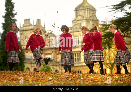 MÄDCHEN AUS WESTONBIRT SCHULE IN DER NÄHE VON TETBURY GLOUCESTERSHIRE UK SPIELEN MIT DEM HERBSTLAUB Stockfoto