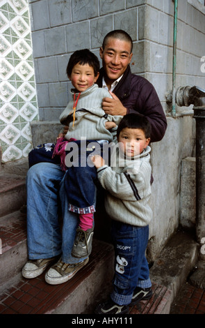 Neu angekommene Flüchtlinge aus Tibet im Aufnahmezentrum in Dharamsala, Himachal Pradesh, Indien. Ein Mann und zwei Kinder sitzen auf Stufen. Stockfoto