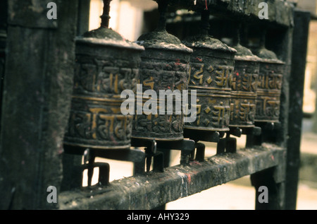 Reihe verwitterter alter buddhistischer Gebetsmühle mit heiligen Inschriften in einem traditionellen Holzrahmen. Stockfoto