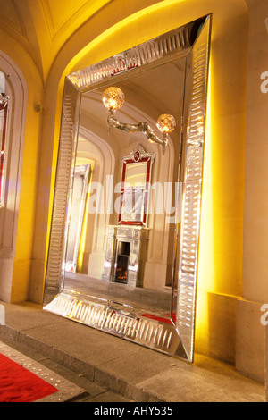 Der Eingang mit Spiegel in Kristall Riesen Armen halten Kandelaber Reflexionen aus einer Hand und einem Kristall Kamin erbaute faseroptische Beleuchtung mit den roten Teppich. Bei der Baccarat Museum, Shop, Restaurant im Hotel de Noailles in Paris. Von Philippe Starck entworfen. Die Baccarat Museumseingang: Kristallspiegel mit einem Kristall-Arm hält eine Kristall-Licht und ein Spiegelbild der Kristall Kamin Stockfoto