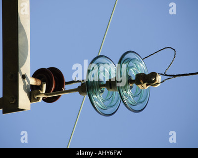 Nahaufnahme der Scheiben am Ende des Overhead, hohe Spannung Stromkabel, treffen auf einen Telegrafenmast. Blauen Himmel dahinter Stockfoto