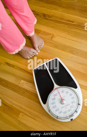 Frau zögerlich auf Skala zu bekommen Stockfoto