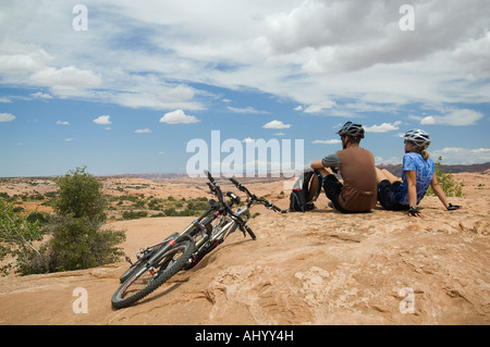 Radfahrer neben Mountainbikes in Wüste sitzt Stockfoto