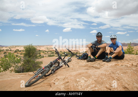 Radfahrer neben Mountainbikes in Wüste sitzt Stockfoto