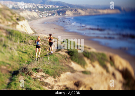 Frauen, die auf Felsen Wasser entlang joggen Stockfoto