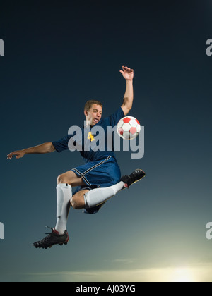 Menschen treten Fußball in Luft Stockfoto