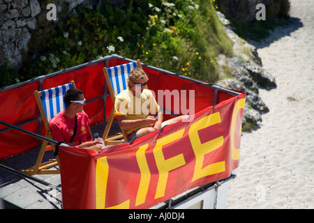 Leben Wachen Rettungsschwimmer 2 zwei junge Männer Männer sitzen in Liegestühlen Liegestühlen am Sandstrand Porthmeor Surfen in St Ives UK GB Stockfoto