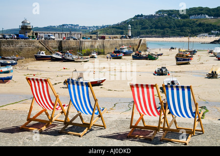 Vier 4 leeren Liegestühle Liegestühle an sonnigen Sommertag auf der Hafenmauer in St Ives Cornwall England UK United Kingdom GB Stockfoto