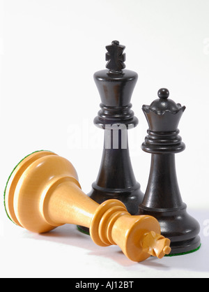 Schachfiguren - schwarz König und Königin bleiben stehen.  Der weiße König hat wie in einer Geste der Resignation gelegt worden Stockfoto