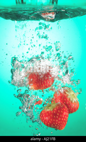 Erdbeeren in farbigem Wasser fallen Stockfoto