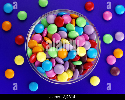 SMARTIES IN EINER SCHÜSSEL AUF EINEM BLAUEN HINTERGRUND MIT ZUFÄLLIGEN Stockfoto