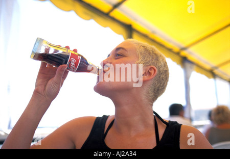 Junge Frau trinkt Flasche Coca Cola Stockfoto