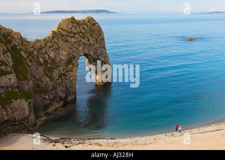 Zwei Menschen stehen auf dominiert der Strand durch die riesigen Felsbogen, Dorset Stockfoto