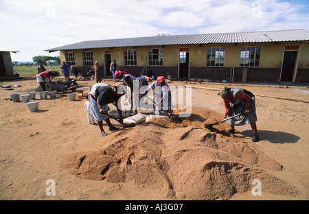 In einem Gemeinschaftsprojekt mischen Frauen Zement für den Bau einer neuen Schule. Eswatini (Swasiland) Stockfoto