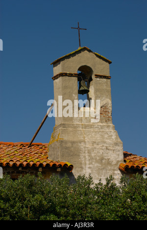 Schmiedeeisernen Kreuz auf dem Backstein und Adobe Glockenturm gegen einen klaren blauen Himmel in der Mission San Juan Capistrano, CA, USA Stockfoto