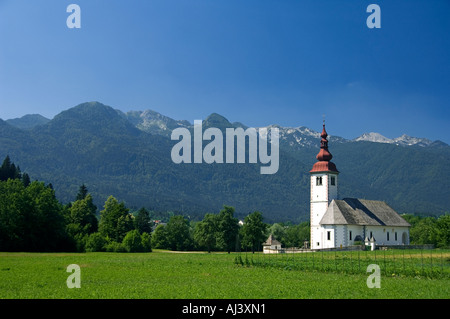 Die Kirche in Bitjne in der Nähe von Bohinj See sticht in krassen Schönheit gegen die umliegenden Berge Stockfoto