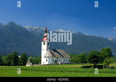 Die Kirche in Bitjne in der Nähe von Bohinj See sticht in krassen Schönheit gegen die umliegenden Berge Stockfoto