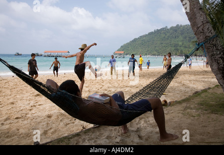 Tourist, lesen ein Buch am Strand und Fußball/Fußball-Spiel am Salang Beach, Salang Tioman Tioman Island, Malaysia. Stockfoto