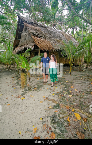 Junges Paar geht weg von ihrem traditionellen Palme Bambus Stroh Bungalow Kosrae Village Resort in Mikronesien Stockfoto