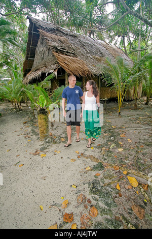 Junges Paar geht weg von ihrem traditionellen Palme Bambus Stroh Bungalow Kosrae Village Resort in Mikronesien Stockfoto