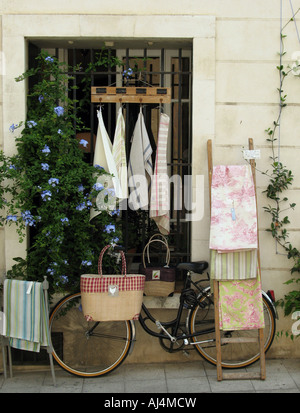 Anordnung der Elemente, die unter anderem ein Fahrrad einige Taschen Geschirrtücher und Tischdecken werden vor einem Geschäft in Arles, Frankreich Stockfoto