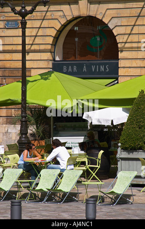 Eine Wein-Bar mit Sitzgelegenheiten außerhalb mit grünen Sonnenschirme Schatten vor der Sonne und zwei Personen sitzen an einem Tisch trinken, Reims, Champagne, Marne, Ardennen, Frankreich Stockfoto