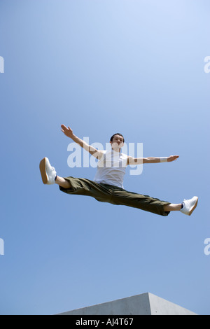 Junger Mann springt und dabei spaltet sich in der Luft Stockfoto