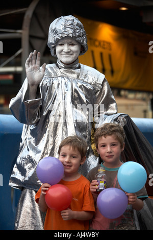 Statue Straßenkünstler mit zwei jungen Kindern Brüder gekleidet in Silber mit Rosen und Luftballons in Sydney NSW, Australien Stockfoto