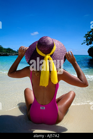 Grand Cayman Sandbar Frau in rosa Anzug lila Hut sitzt am Strand von hinten erschossen Stockfoto