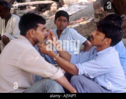 Indischer Mann rasieren außerhalb in Varanasi Stockfoto