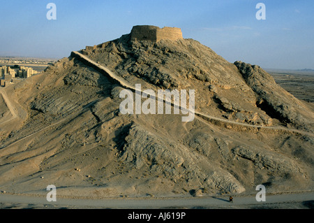 Ein einsamer Motorradfahrer wird durch das Ausmaß einer der Türme des Schweigens am Rande von Yazd in Zentraliran dominiert. Stockfoto