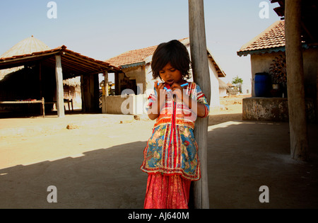 Junge Harijan Stammeskind steht vor Schlammhütten in Ludia Village, nr Khavda, Kutch Bezirk, Gujarat, Indien Stockfoto