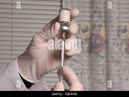 Arzthandschuhe Hand halten Spritze mit Impfstoff, symbolisiert Gesundheitswesen, Immunisierung und öffentliche Gesundheit in den USA. Stockfoto
